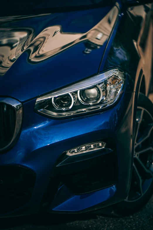 blue car front end with chrome rim and hood reflecting lights