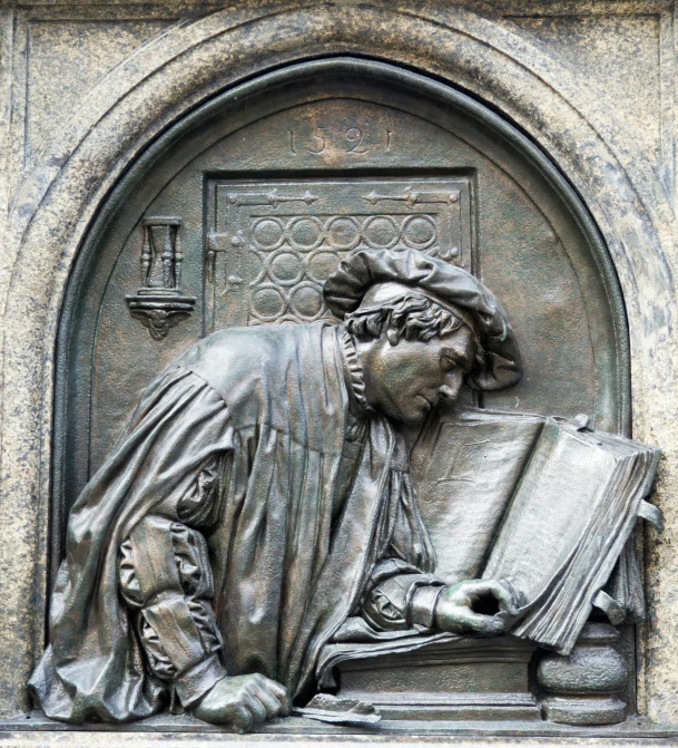 a close up of a metal statue of a person reading