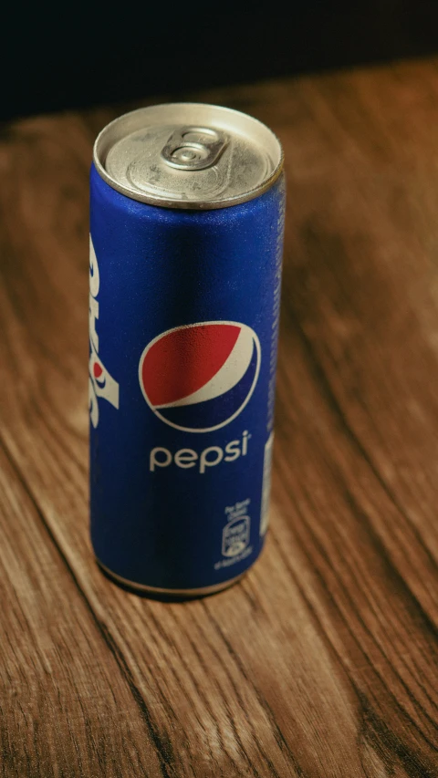 a can of pepsi on top of a wooden table