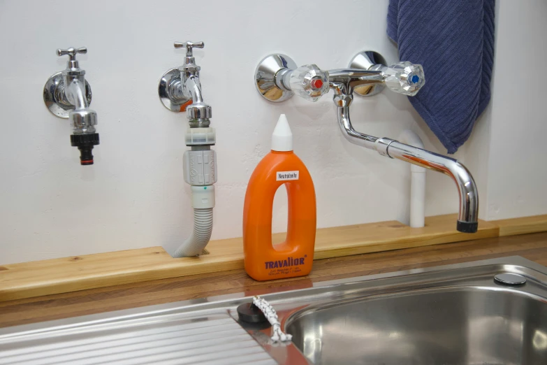 orange bottle of liquid next to water faucet on sink