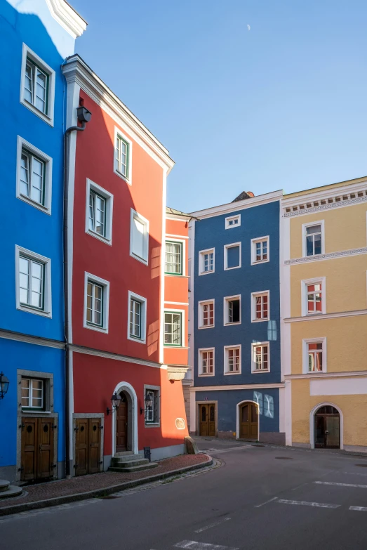 three buildings are painted a different color on the same street