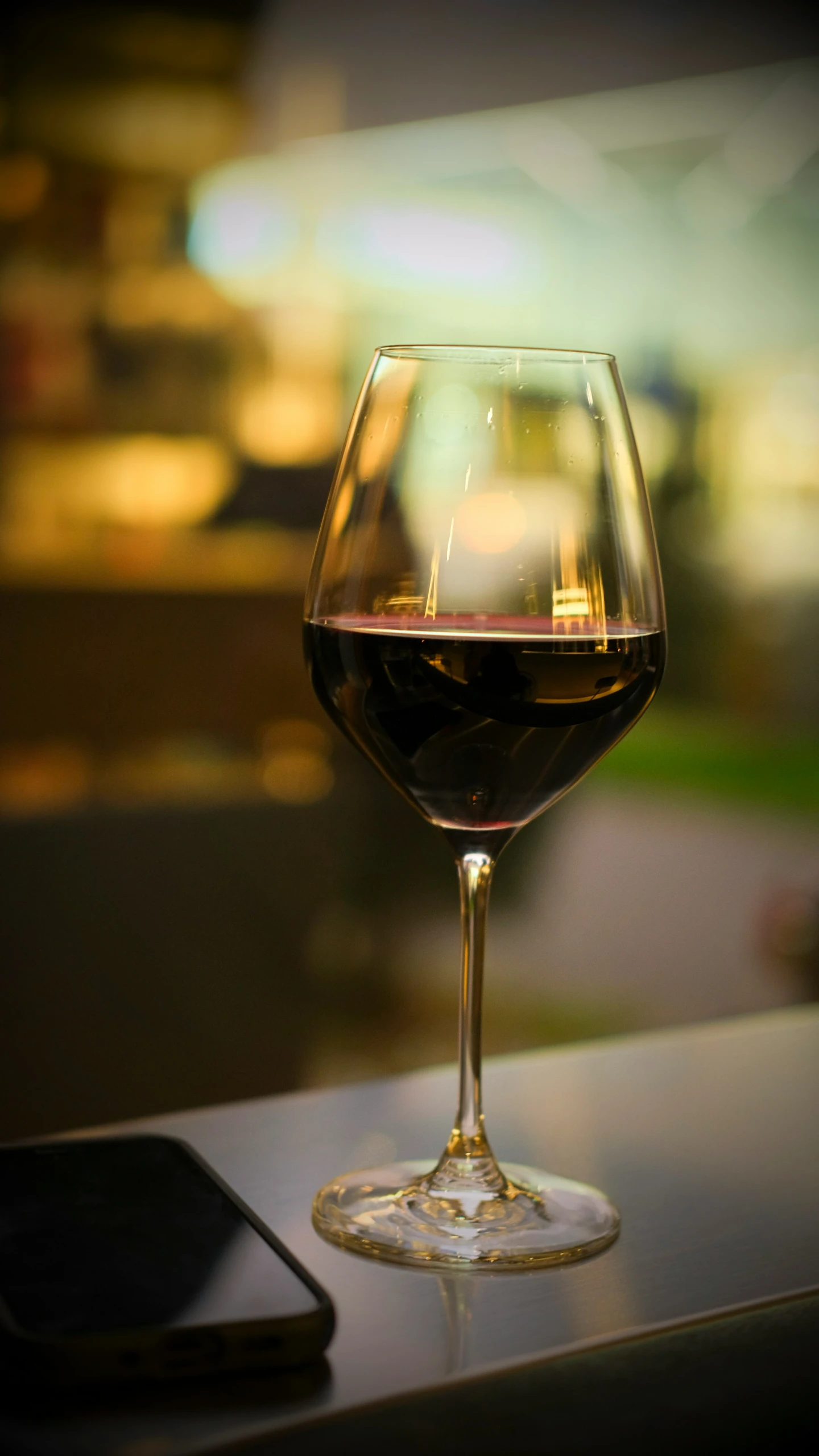 a close up view of a wine glass with a cell phone next to it