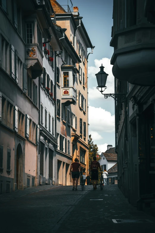 two people walk along an alley with tall buildings on both sides