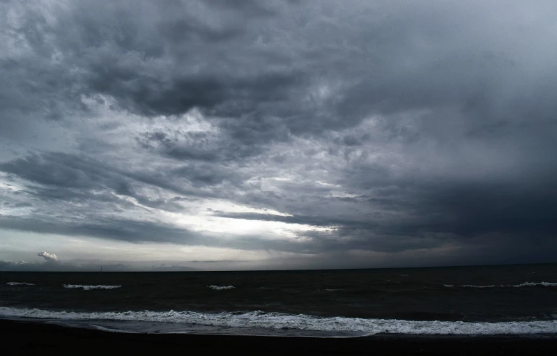 stormy skies over ocean water with one boat on shore