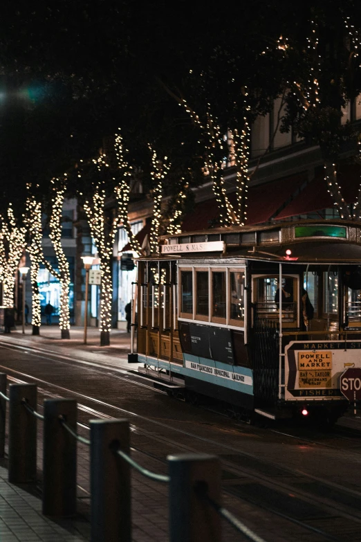 a trolley on an urban street with christmas lights