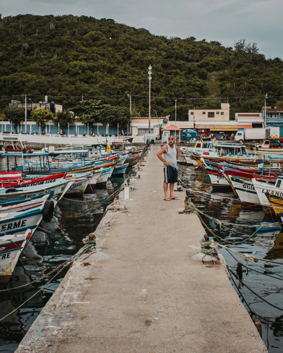 a person is standing on the dock next to several boats