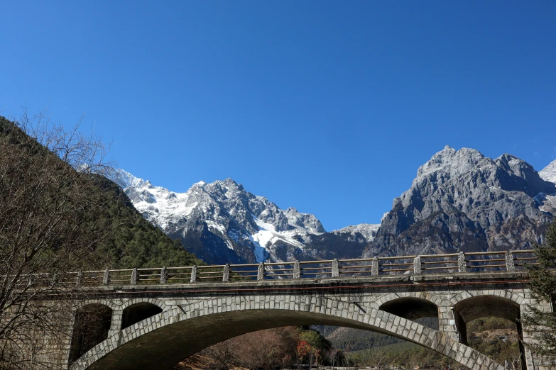 the mountains and the bridge are clear, blue, with snow on them