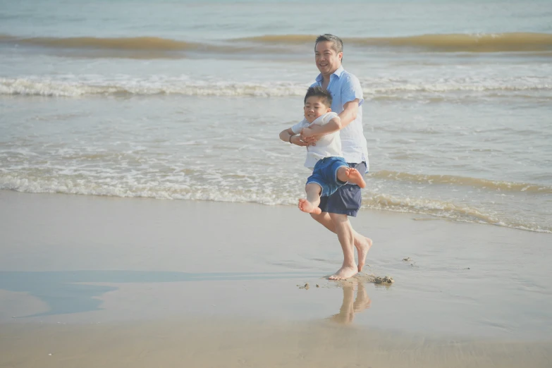 an adult carrying a young child on a beach