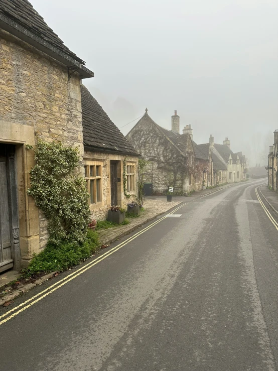 an empty city street that has stone houses in the background