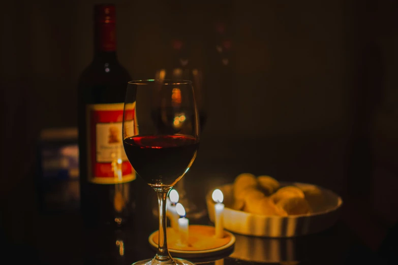 a glass and bottle with red wine on a table