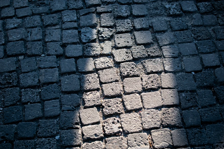 a shadow of a person walking down a brick street
