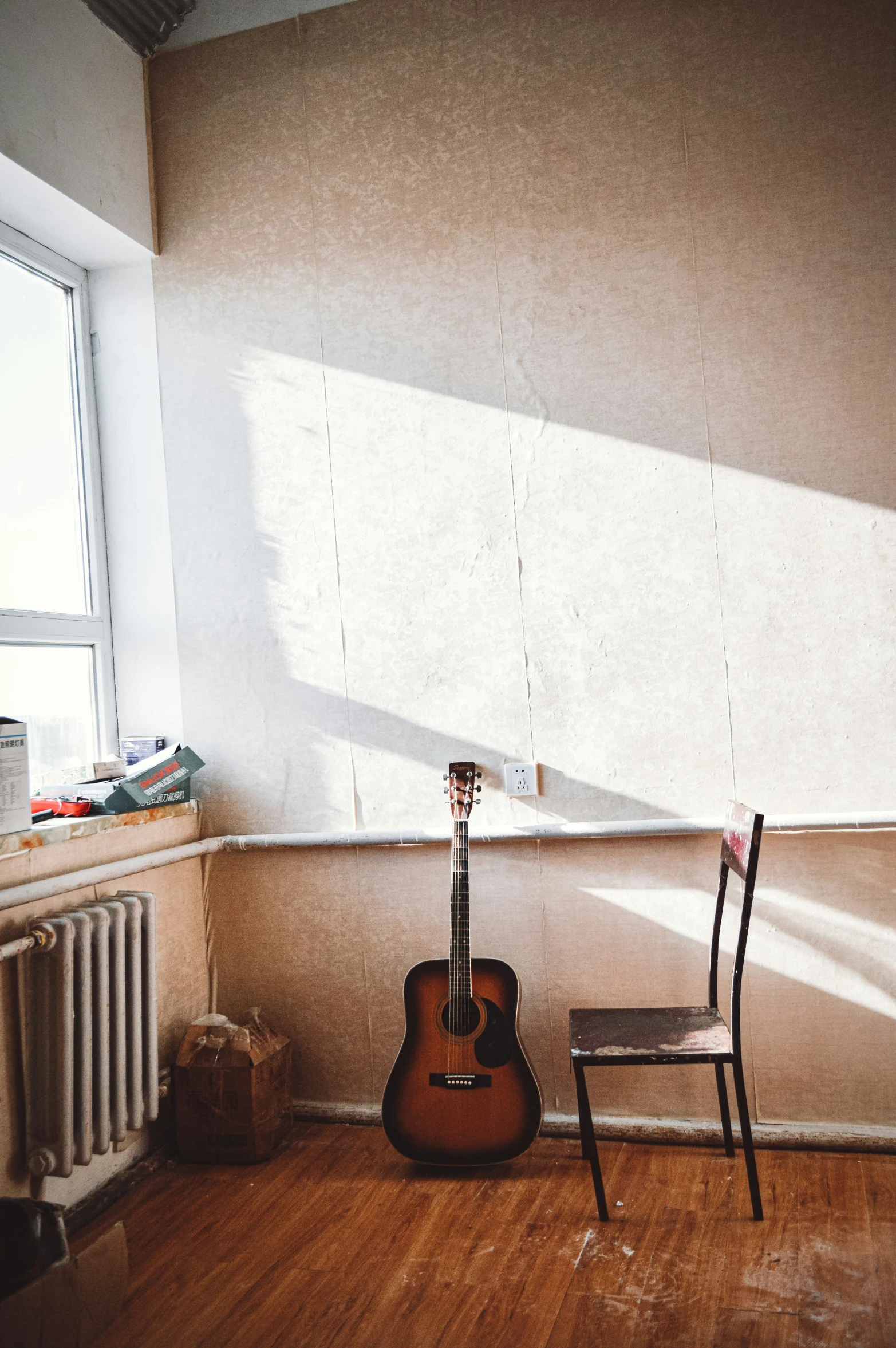 a guitar leaning up against the wall near a chair