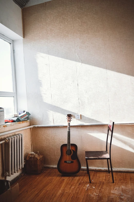 a guitar leaning up against the wall near a chair