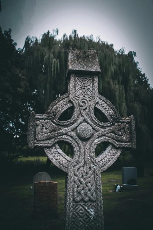 this is a very unusual looking cross with trees in the background