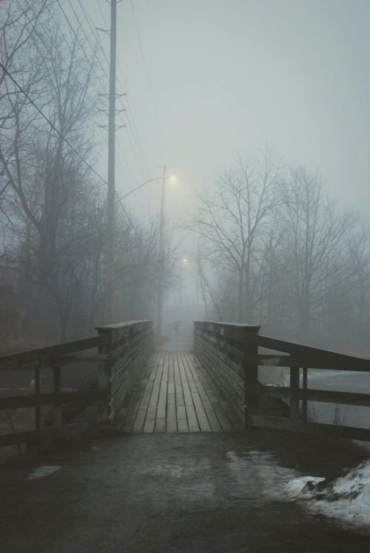 a bridge in a foggy forest with some poles