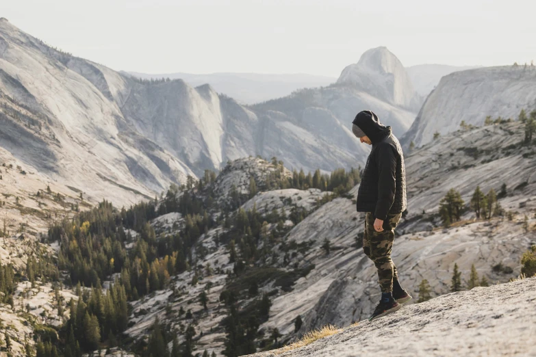 a man standing on a mountain ledge looking at the mountains