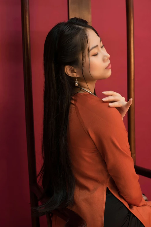 woman sitting in an elegant chair with a red background