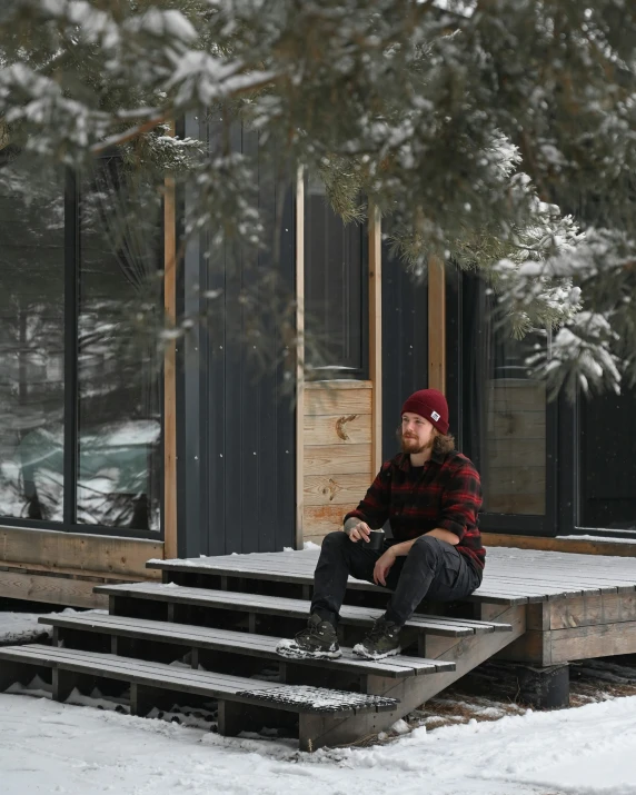 a man in winter clothes sitting on steps in front of a building