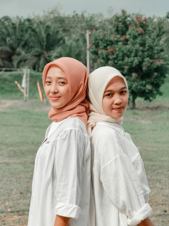 two women standing on the ground holding an umbrella