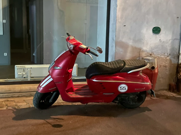 a red motor scooter parked on the side of a street