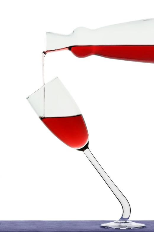 a close - up of two wine glasses with red wine being poured into it