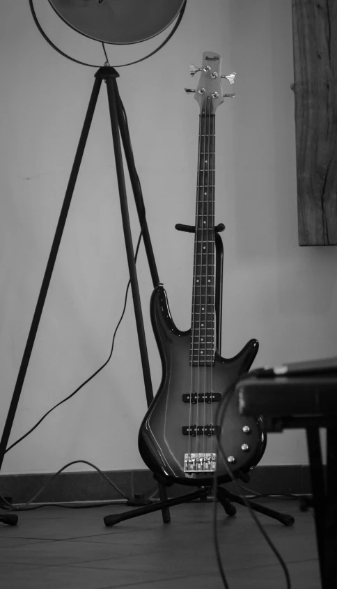a bass guitar with a stand on the floor and two other music equipment