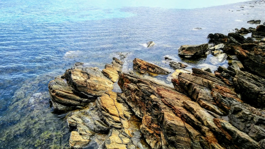 large stones in the water and trees are behind them