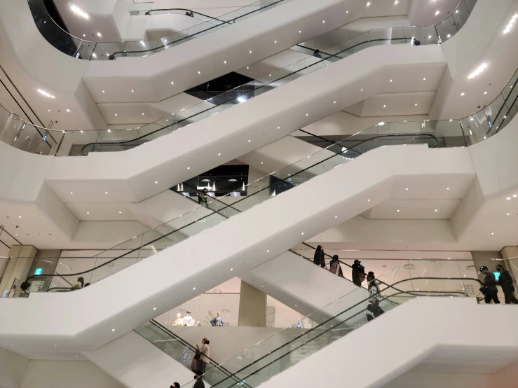 people walking on a white stair case and several others are looking up