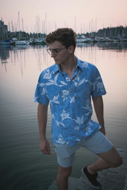 man in hawaiian shirt by water with boats