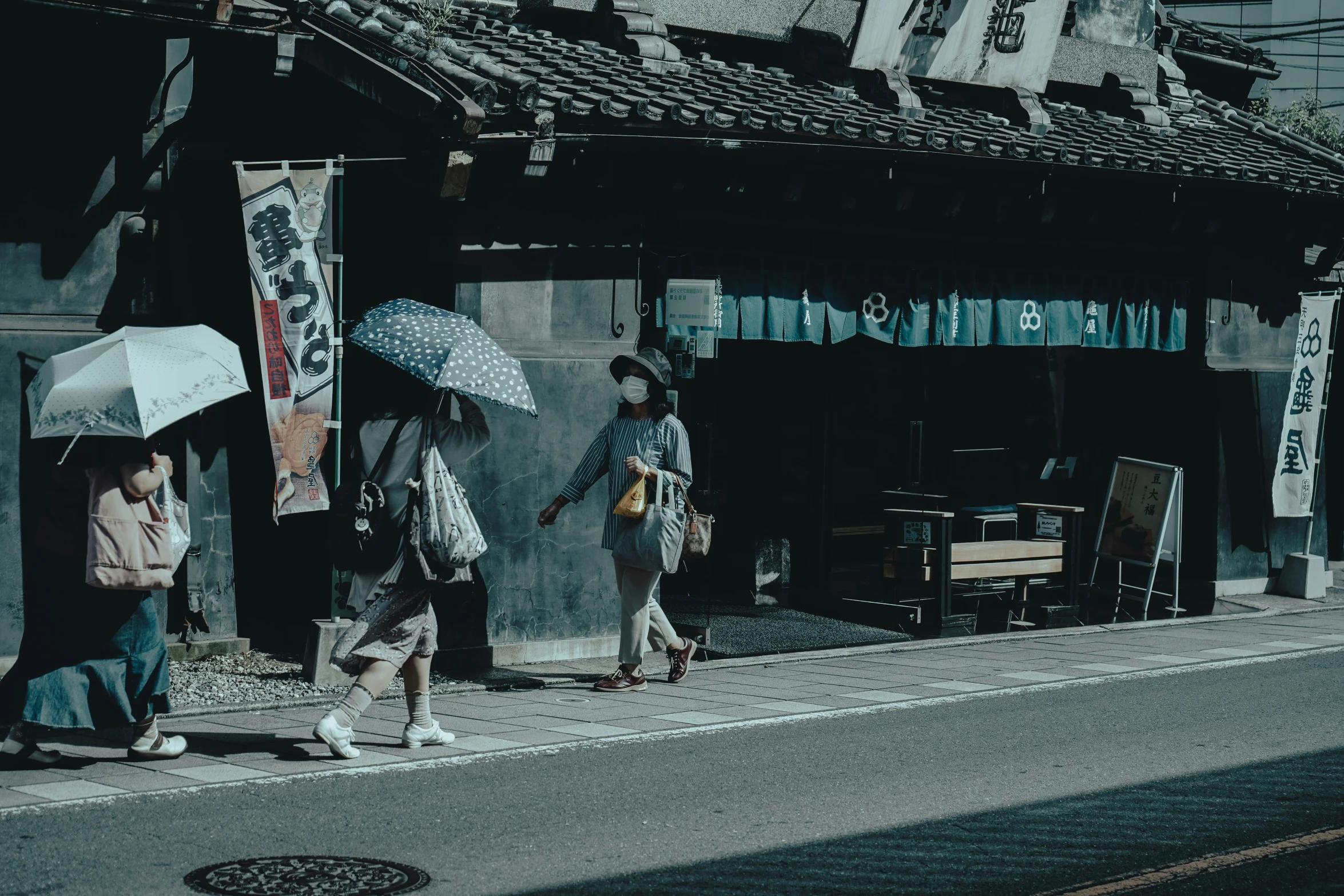 some people walk down the street with umbrellas