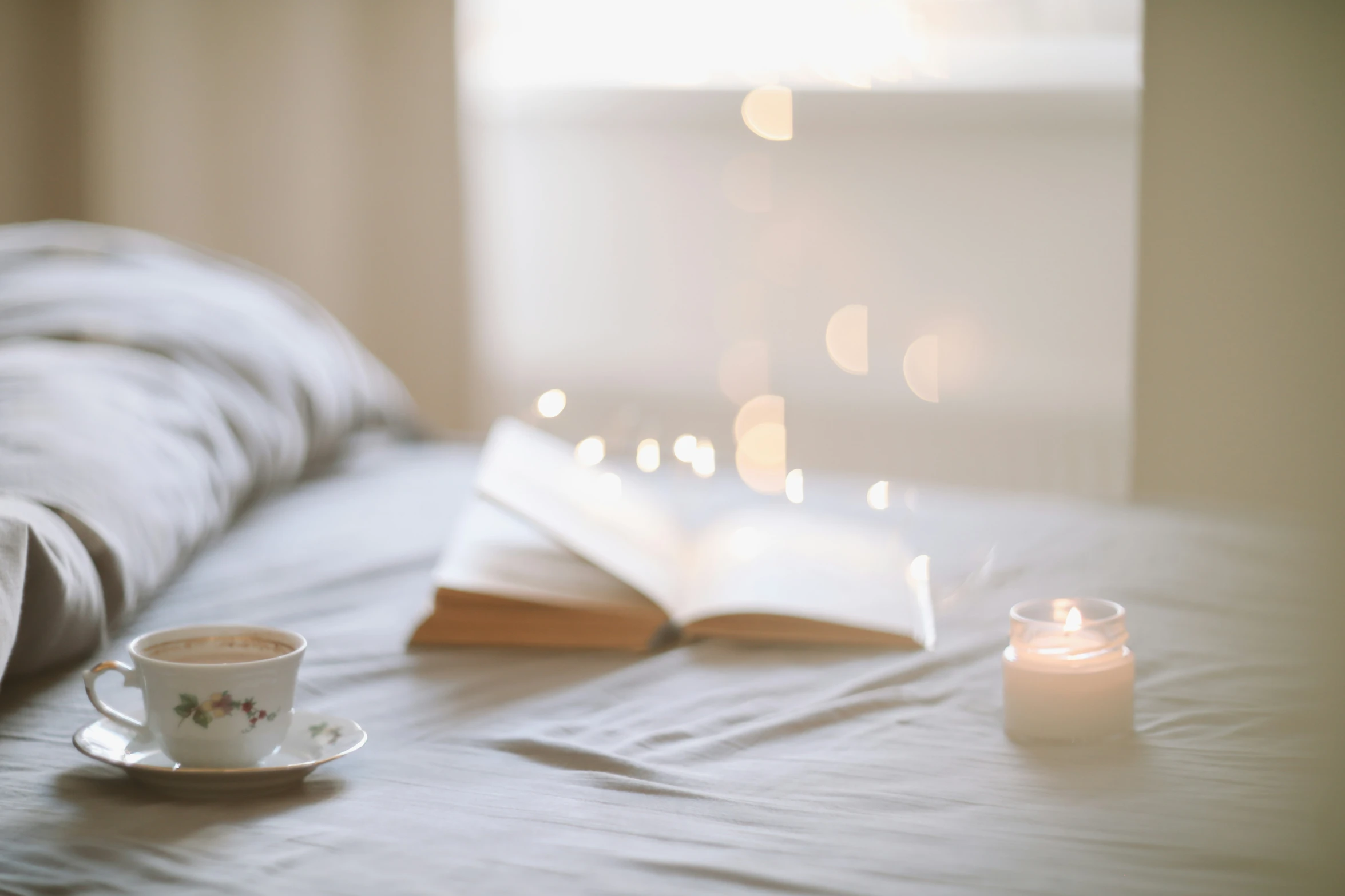 a coffee cup and a book are on a bed