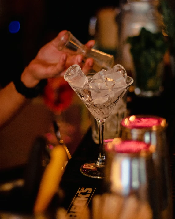 the bartender is pouring the drink from the glass into the goblet