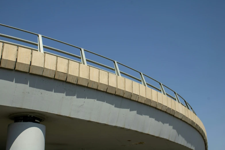 a skateboarder in blue jumping off a very tall bridge