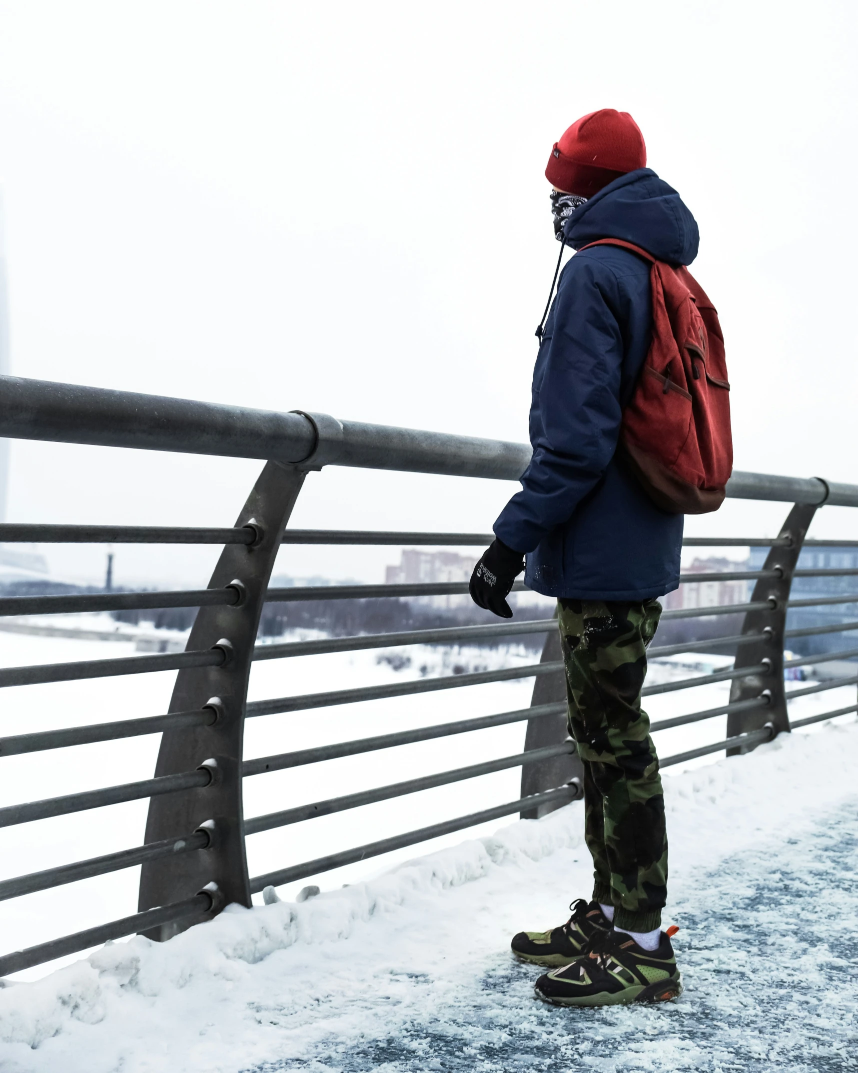 a man standing on a bridge wearing a red backpack