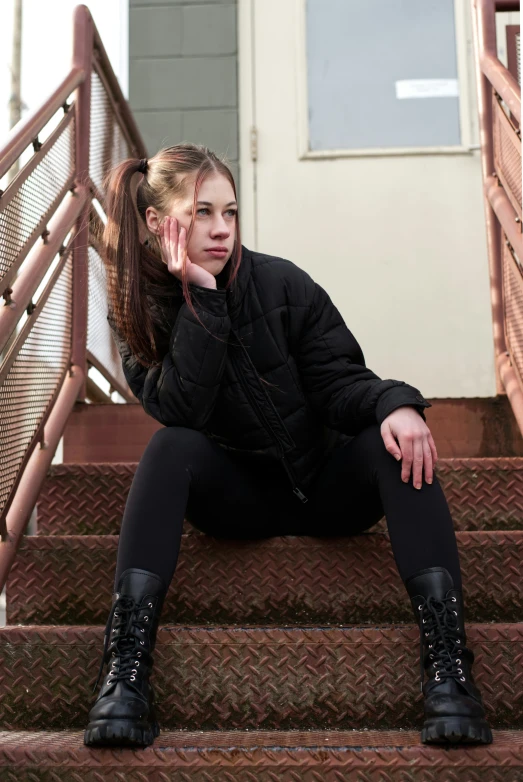 a woman sitting on the steps with her hand on her nose