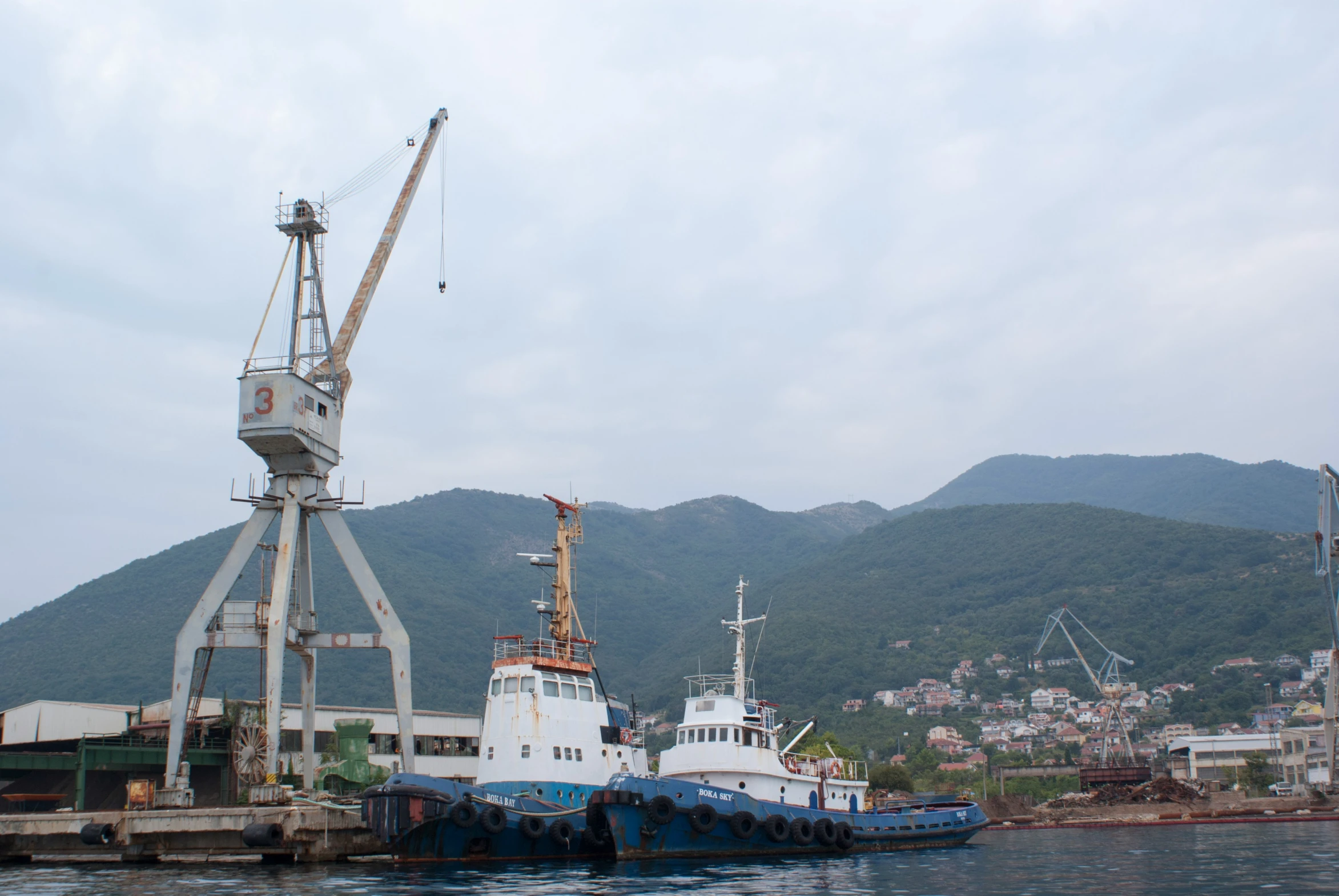 a boat docked next to a large industrial dock