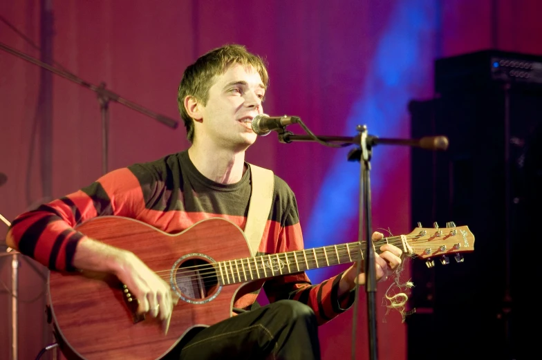 the man is playing an acoustic guitar while performing