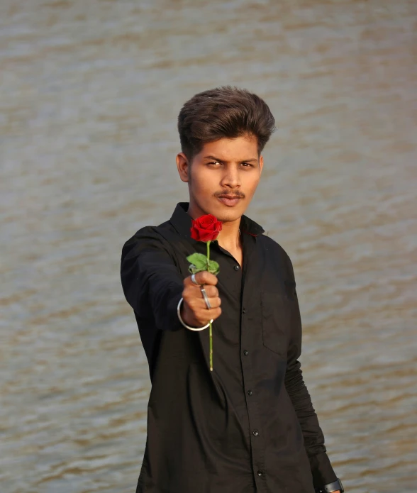 man in black shirt with flower pointing at the camera