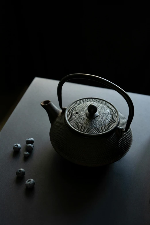 a tea pot sits on a table with its spoon beside it