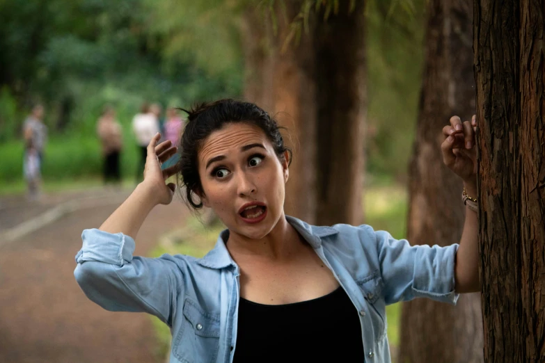 a woman is making a face near a tree