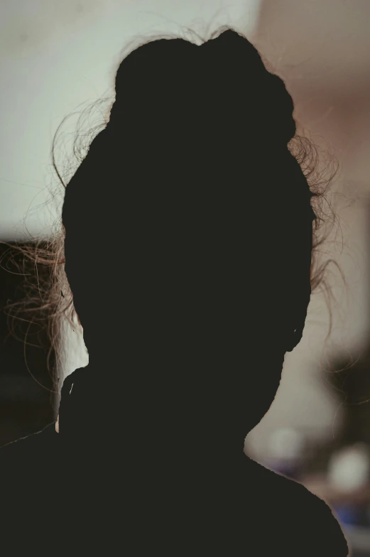 a shadow of a woman's head in dark lighting