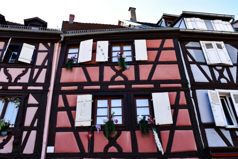 windows with shutters are on the side of an old building