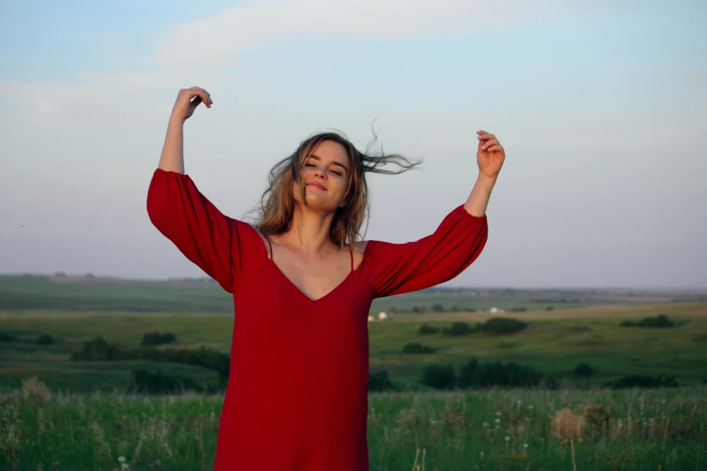 there is a woman with arms outstretched on a green field