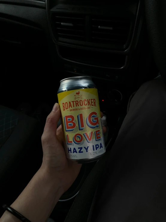 a person holding up an opened can in the back of their car