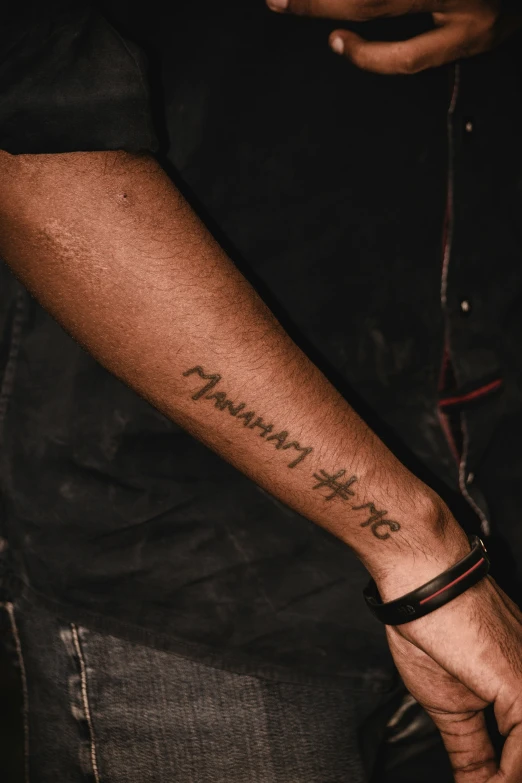 a person wearing a wrist tattoo, with the words family written on it