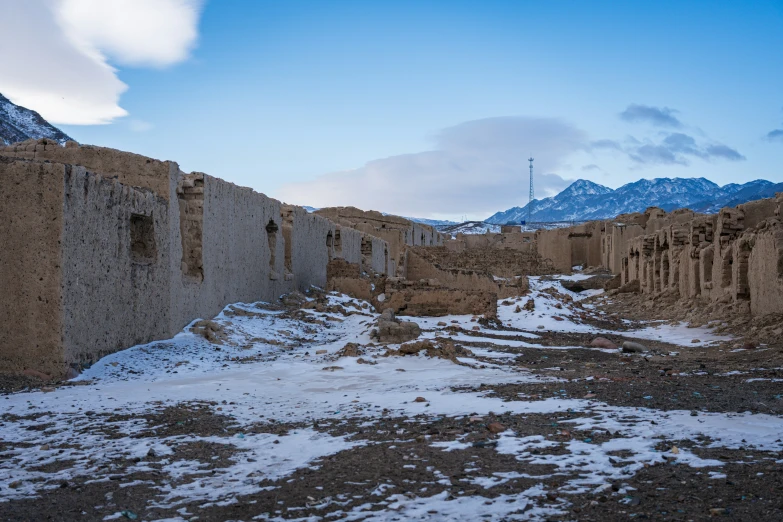 a snow covered street between two walls and a building