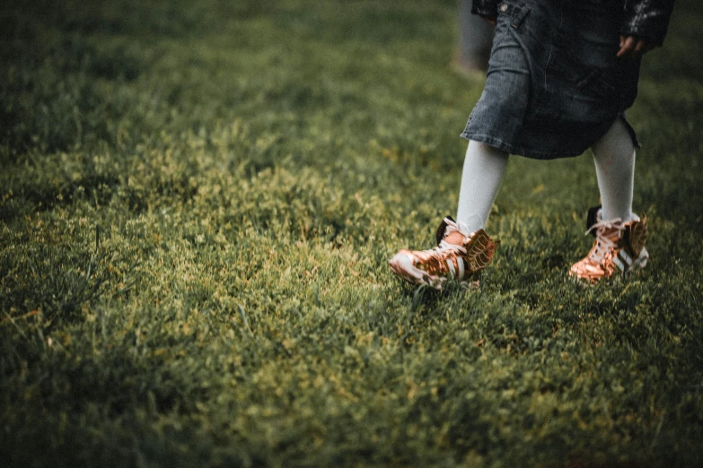 a person walking in the grass with orange and white shoes