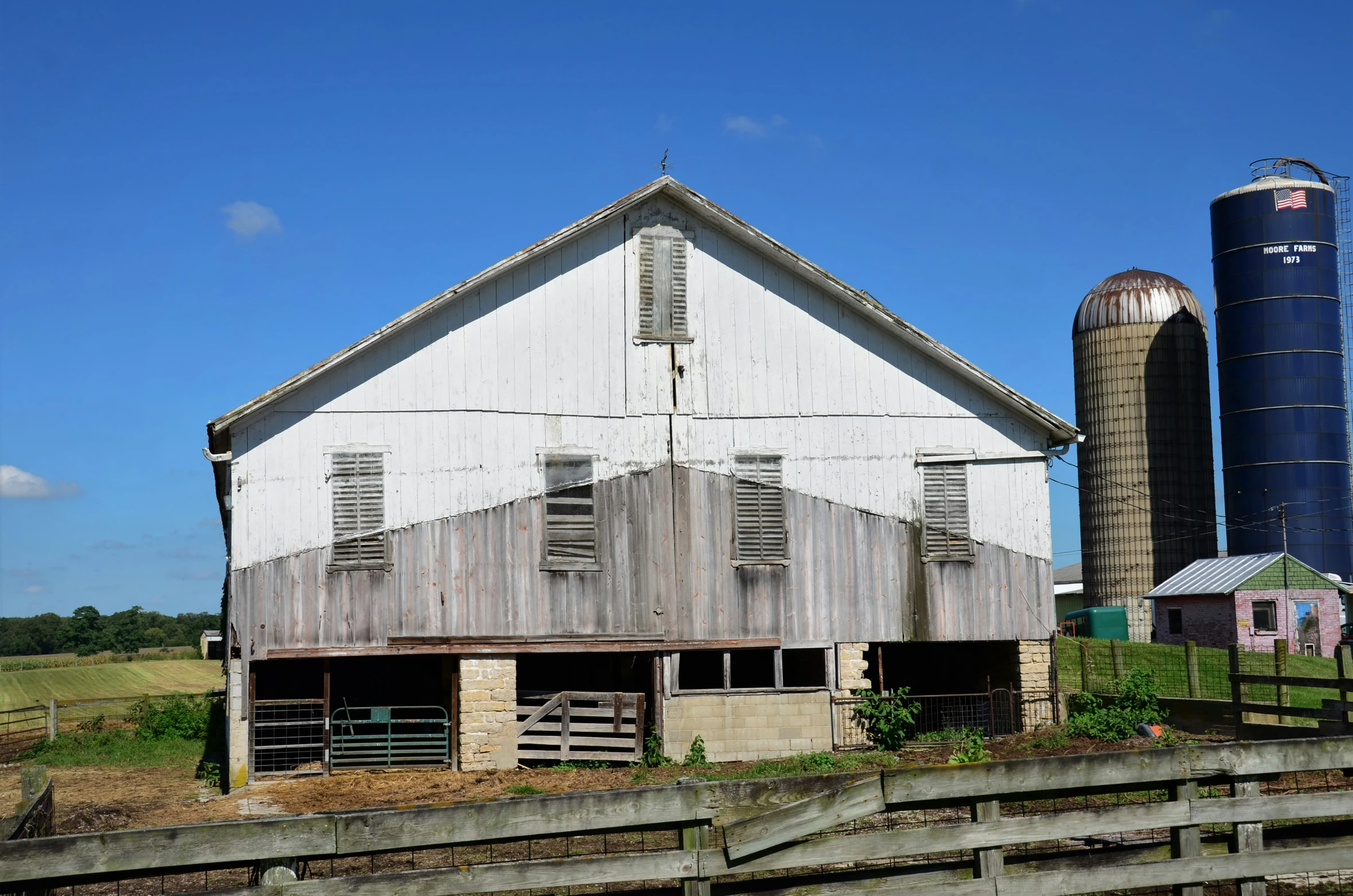 a wooden barn next to a metal silo