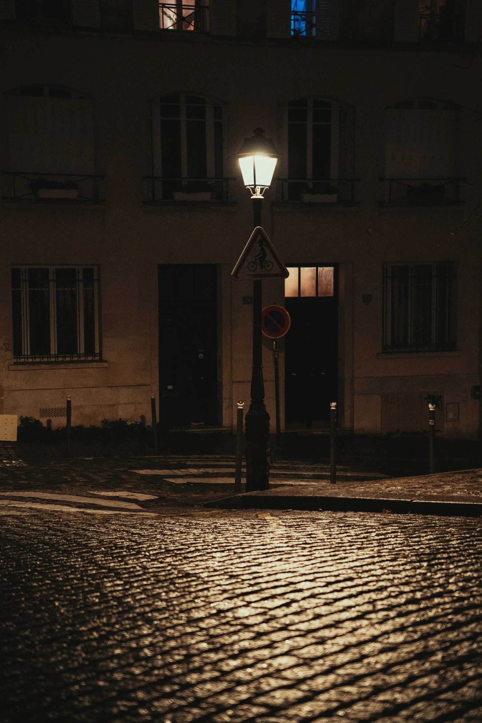 a streetlight shining through the windows of an apartment building