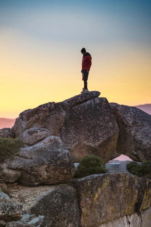 a person standing on a rock at the top of a mountain